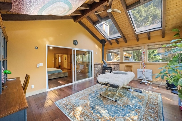 sunroom / solarium with ceiling fan, a wood stove, and vaulted ceiling with skylight