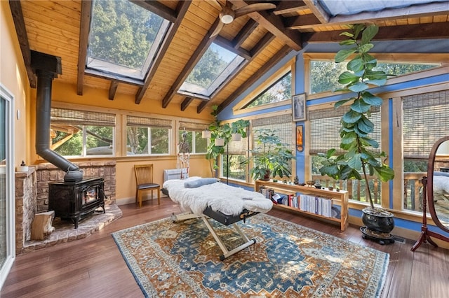 sunroom / solarium featuring lofted ceiling with skylight, a wood stove, and wood ceiling