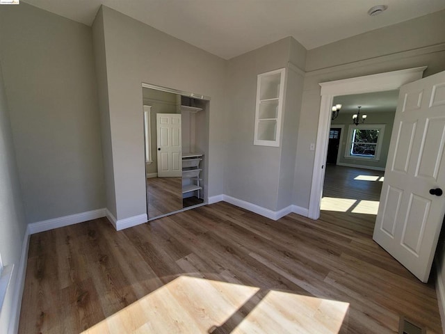 unfurnished bedroom with a closet, a notable chandelier, and hardwood / wood-style flooring