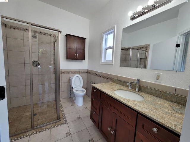 bathroom with tile patterned floors, walk in shower, vanity, tile walls, and toilet