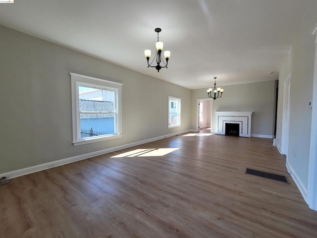 unfurnished living room with dark wood-type flooring, a brick fireplace, and a notable chandelier