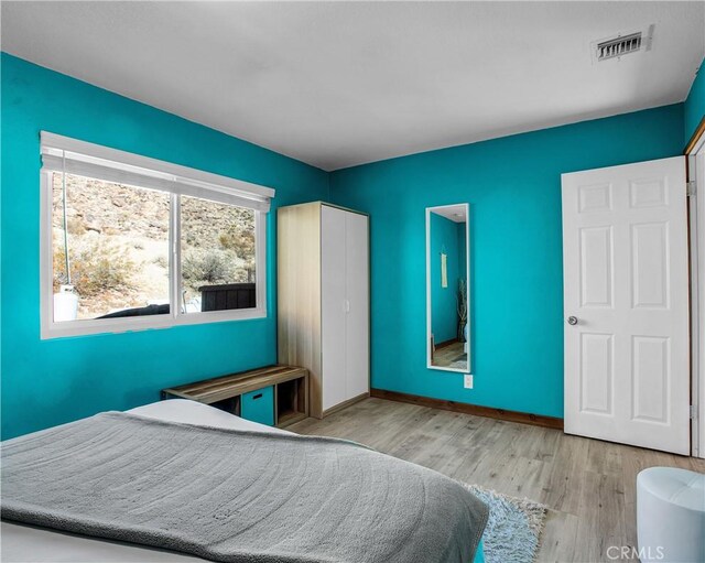 bedroom featuring baseboards, wood finished floors, and visible vents