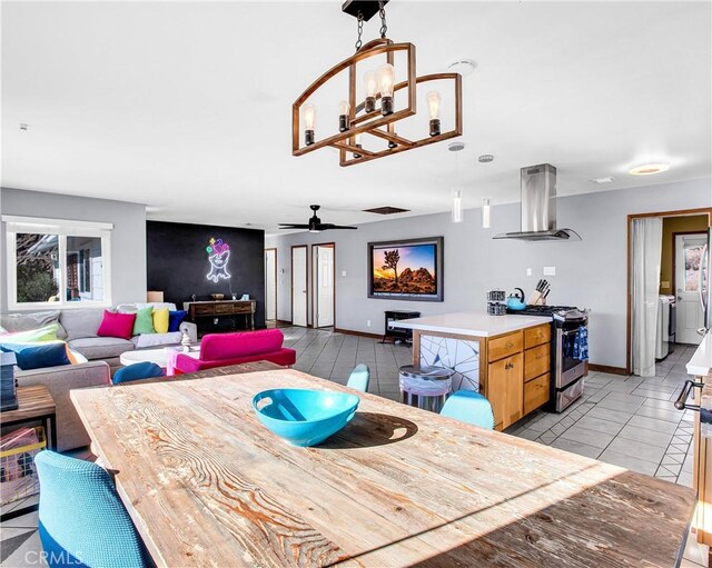 dining area featuring light tile patterned floors, baseboards, washer and clothes dryer, and ceiling fan with notable chandelier