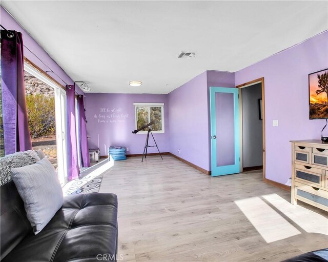 living area with light wood-style floors, baseboards, and visible vents