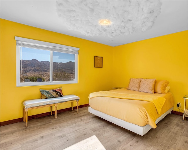 bedroom featuring light hardwood / wood-style flooring and a mountain view