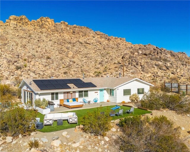 back of house with a yard, fence, outdoor lounge area, and solar panels