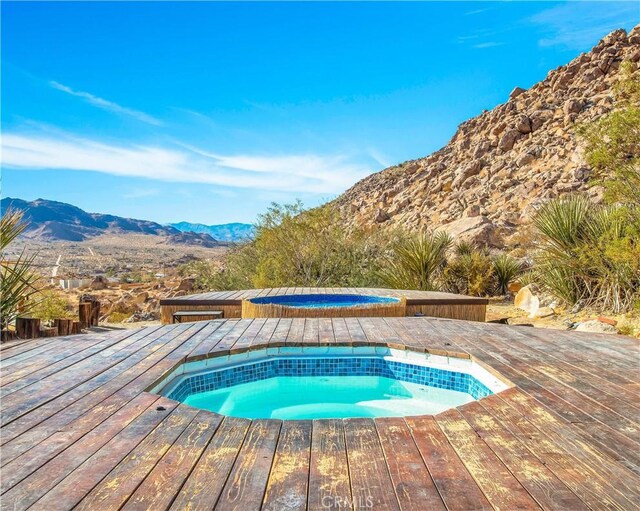 view of swimming pool featuring an in ground hot tub and a deck with mountain view