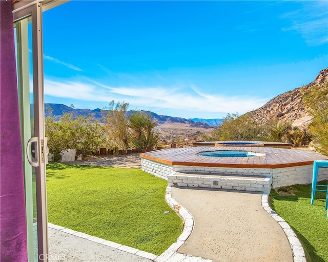 view of community featuring a yard, a mountain view, and a patio