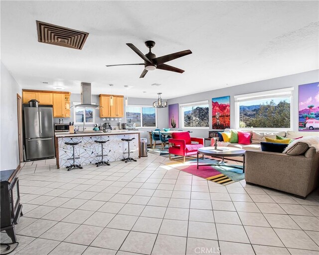 living room featuring visible vents, light tile patterned floors, and ceiling fan with notable chandelier