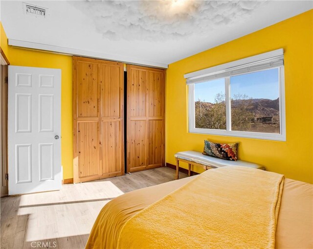 bedroom featuring baseboards, a closet, light wood finished floors, and visible vents