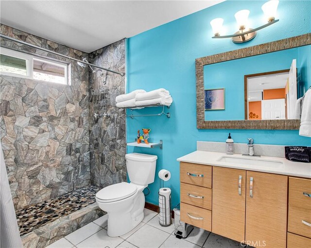 full bath with vanity, tile patterned flooring, a tile shower, and toilet