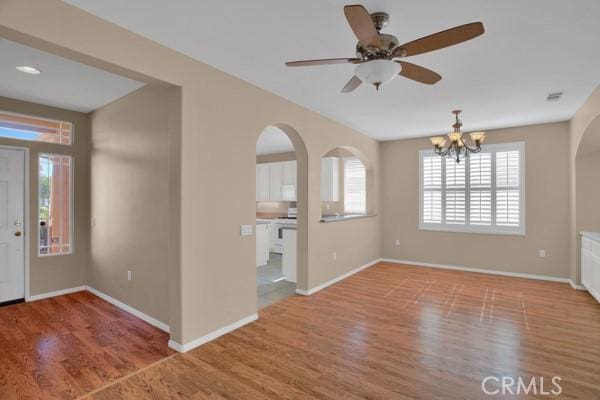 foyer entrance featuring ceiling fan with notable chandelier, light hardwood / wood-style flooring, and a healthy amount of sunlight