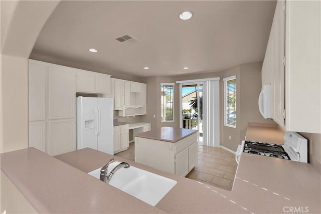 kitchen featuring sink, light tile patterned floors, a kitchen island, white appliances, and white cabinets