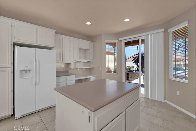 kitchen featuring white cabinetry, white fridge with ice dispenser, a kitchen island, and plenty of natural light