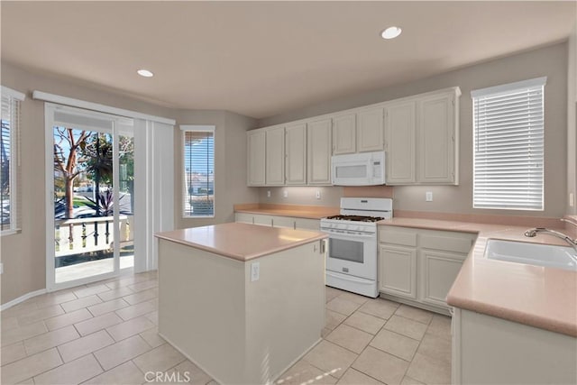 kitchen featuring white appliances, sink, light tile patterned floors, white cabinets, and a kitchen island