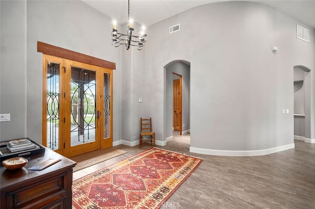 entryway with hardwood / wood-style floors, a notable chandelier, and high vaulted ceiling