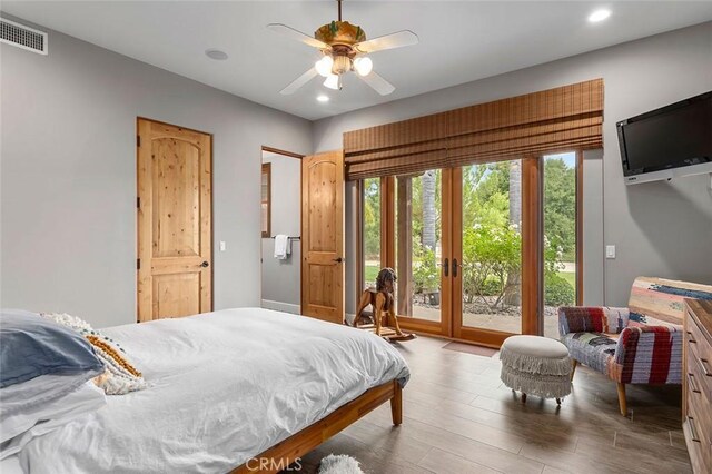 bedroom with ceiling fan, access to outside, multiple windows, and hardwood / wood-style floors