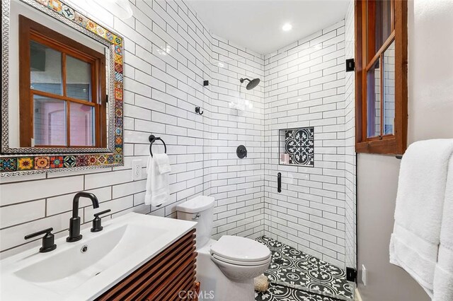 bathroom featuring a shower with door, vanity, decorative backsplash, and toilet