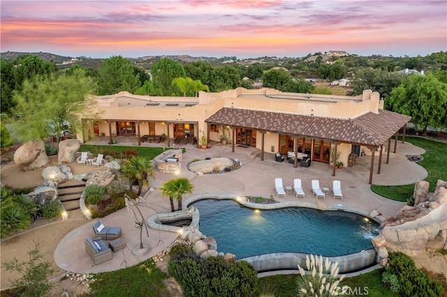 pool at dusk featuring a patio