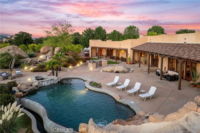 pool at dusk with a patio and a fire pit