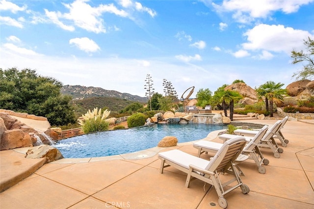 view of swimming pool featuring a patio area, a mountain view, and pool water feature