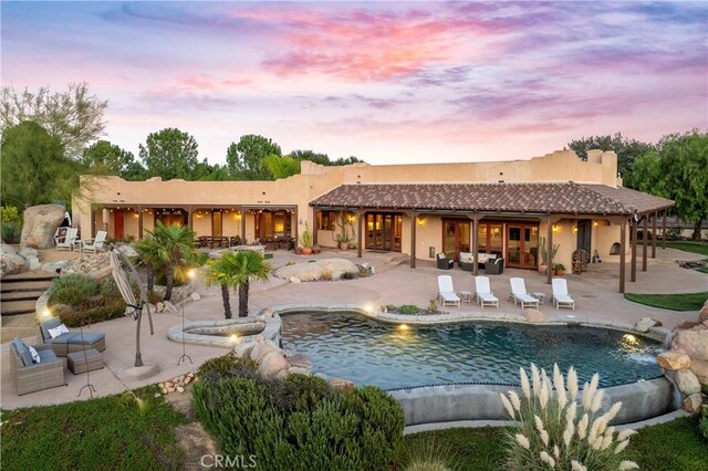 pool at dusk featuring a patio