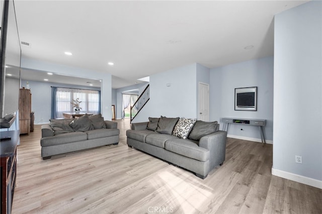 living area with recessed lighting, baseboards, stairway, and light wood finished floors