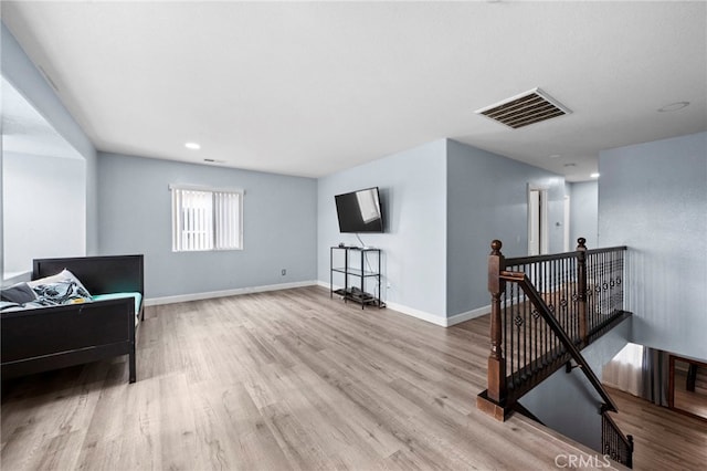 sitting room featuring light wood-style flooring, visible vents, baseboards, and an upstairs landing