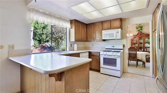 kitchen featuring kitchen peninsula, sink, a breakfast bar, light tile patterned floors, and white appliances