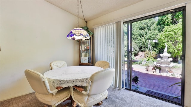 carpeted dining room with lofted ceiling