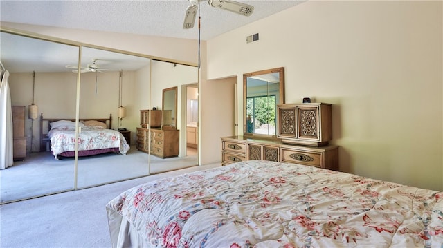 bedroom with a closet, light carpet, vaulted ceiling, a textured ceiling, and ceiling fan