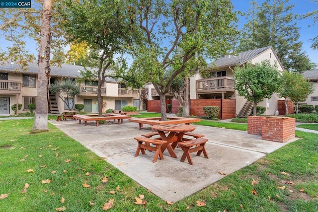 view of property's community featuring a lawn and a patio