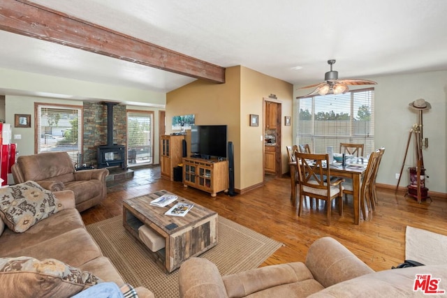 living room with wood-type flooring, a wealth of natural light, and a wood stove