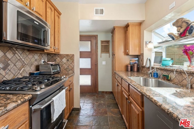 kitchen with decorative backsplash, stainless steel appliances, sink, and light stone counters