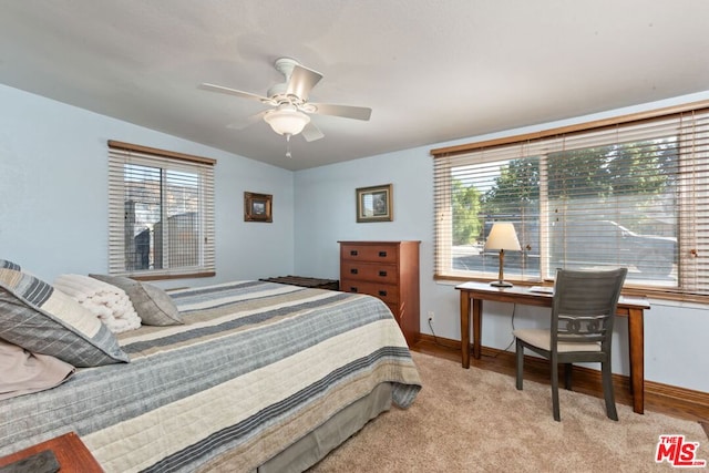 bedroom featuring ceiling fan, multiple windows, and light colored carpet