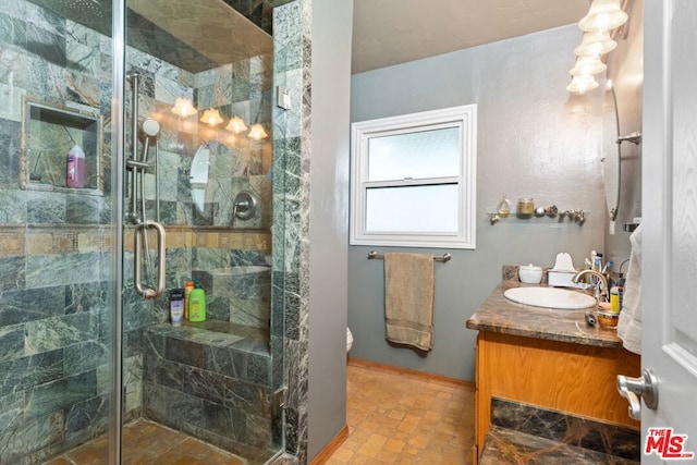 bathroom featuring a shower with door, vanity, and toilet