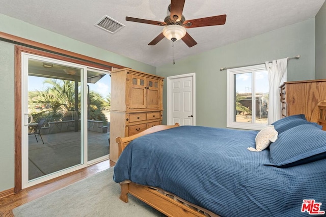 bedroom featuring light hardwood / wood-style floors, a textured ceiling, access to outside, and ceiling fan