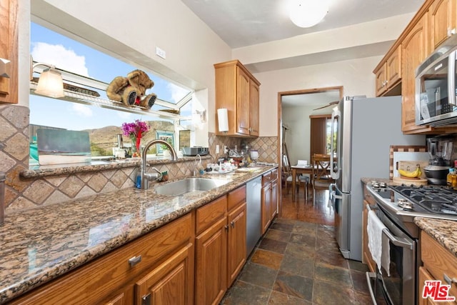 kitchen featuring stone countertops, stainless steel appliances, decorative backsplash, and sink