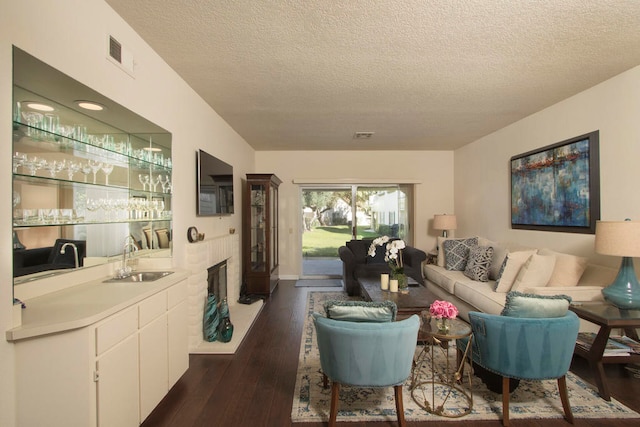 living room featuring wet bar, a textured ceiling, and dark hardwood / wood-style floors