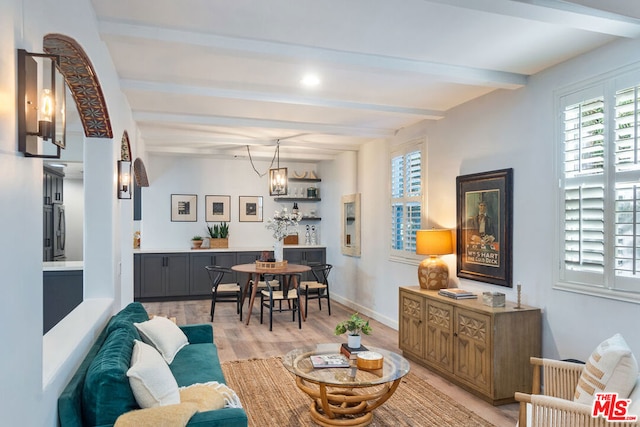 living room featuring beam ceiling, an inviting chandelier, and light hardwood / wood-style flooring