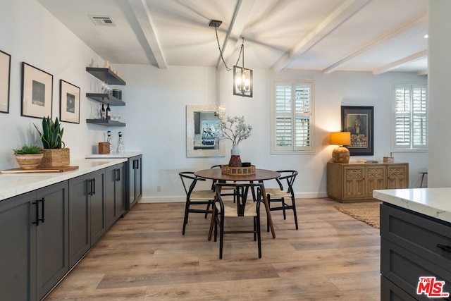 dining room featuring a wealth of natural light, beamed ceiling, a chandelier, and light wood-type flooring