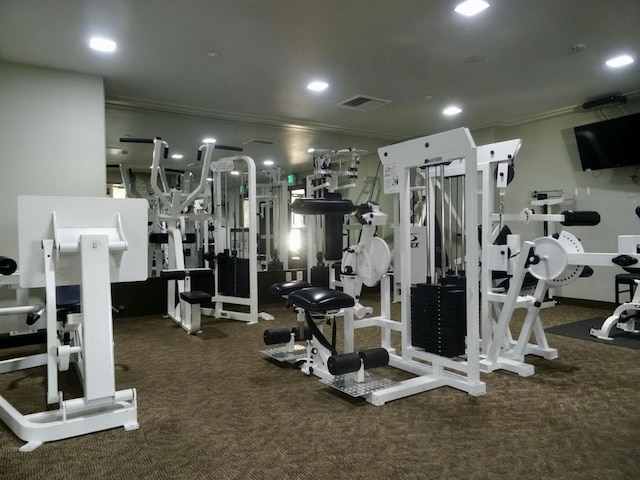 exercise room featuring crown molding and dark colored carpet