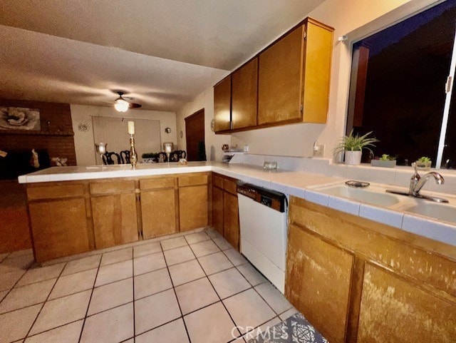 kitchen with sink, white dishwasher, tile counters, light tile patterned flooring, and kitchen peninsula