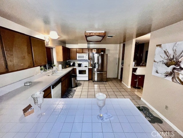 kitchen with light tile patterned flooring, sink, and white appliances