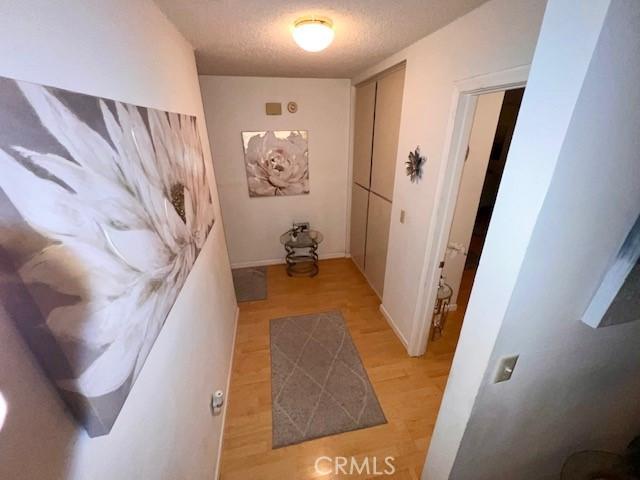 corridor featuring light hardwood / wood-style floors and a textured ceiling