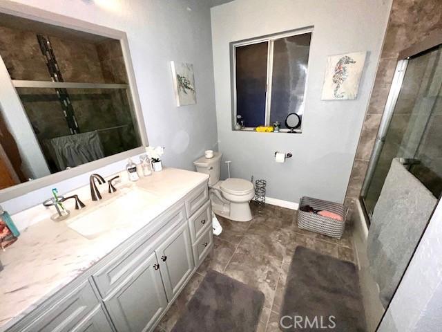 full bathroom featuring vanity, shower / bath combination with glass door, and toilet