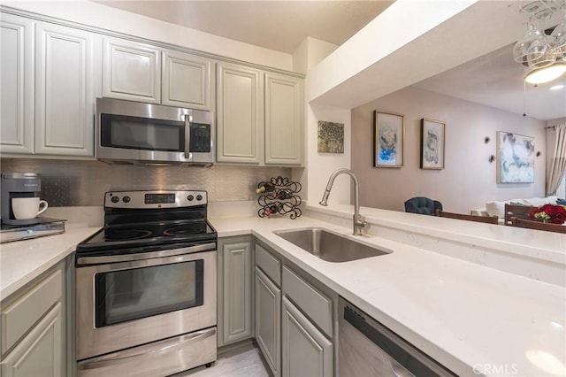 kitchen featuring appliances with stainless steel finishes, tasteful backsplash, sink, kitchen peninsula, and gray cabinetry