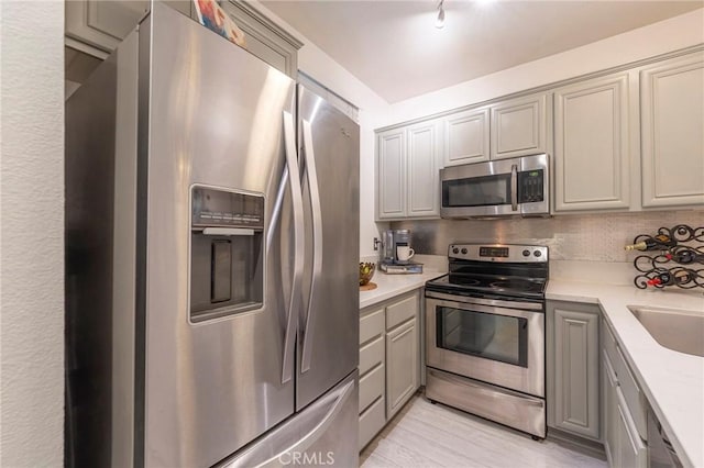 kitchen featuring sink, gray cabinets, decorative backsplash, and appliances with stainless steel finishes