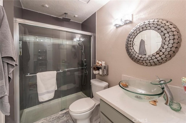 bathroom with vanity, toilet, a textured ceiling, and an enclosed shower