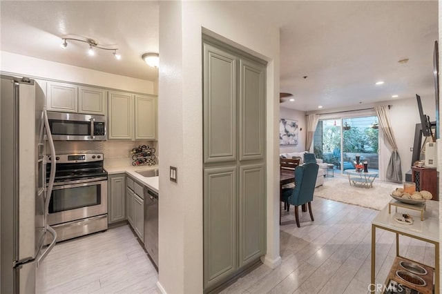 kitchen featuring decorative backsplash, sink, light hardwood / wood-style flooring, and stainless steel appliances